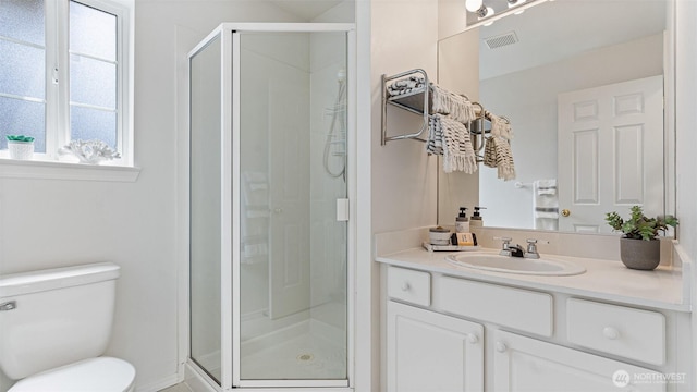 full bathroom with vanity, a shower stall, toilet, and visible vents