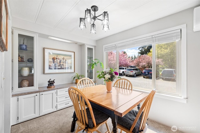 dining space featuring light colored carpet and a notable chandelier