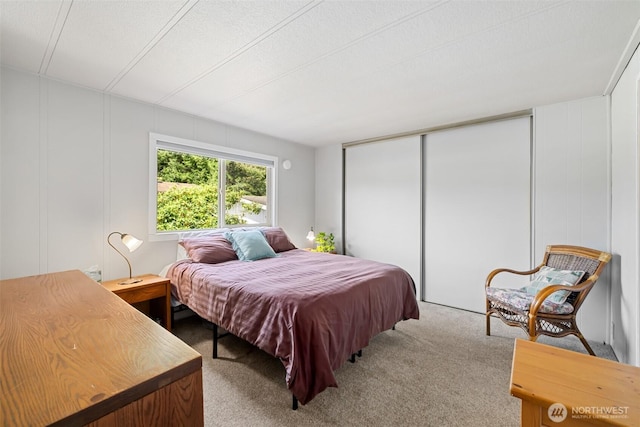 bedroom with carpet floors, a decorative wall, and a closet