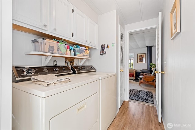washroom featuring cabinet space, crown molding, washing machine and dryer, and light wood-style flooring