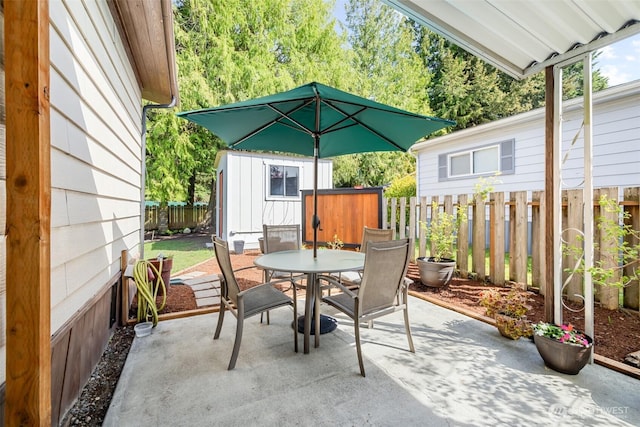 view of patio featuring an outbuilding, outdoor dining area, a fenced backyard, and a shed