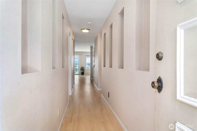 corridor featuring baseboards and light wood-style flooring