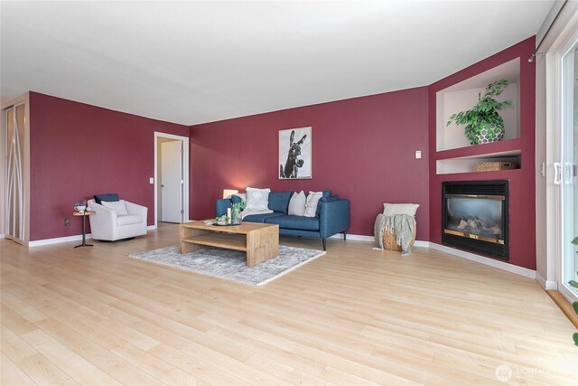 living room with baseboards, a large fireplace, wood finished floors, and an accent wall
