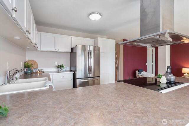 kitchen with freestanding refrigerator, white cabinetry, a sink, and island exhaust hood