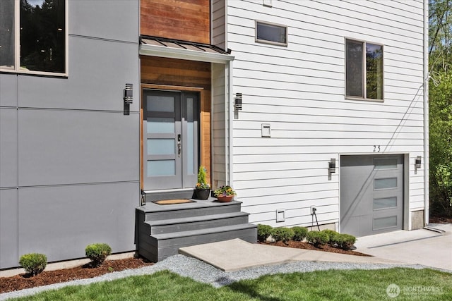 doorway to property featuring concrete driveway, a standing seam roof, metal roof, and a garage