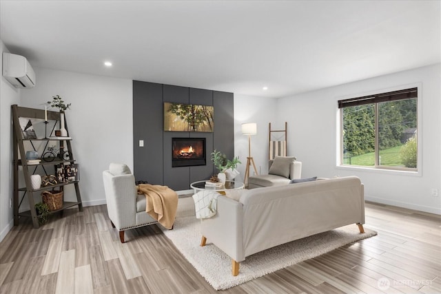 living room featuring light wood-style floors, a large fireplace, baseboards, and a wall mounted AC