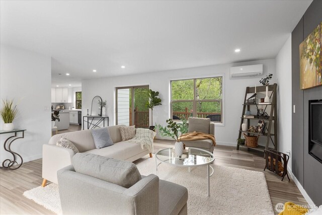 living area with an AC wall unit, baseboards, recessed lighting, and wood finished floors