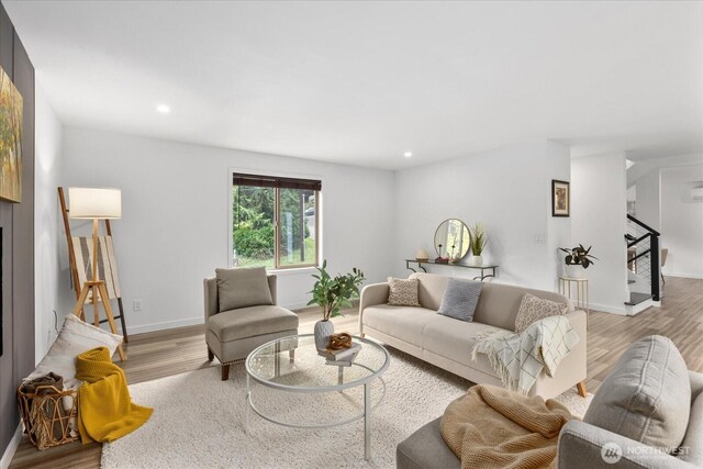 living area with light wood-type flooring, recessed lighting, baseboards, and stairway