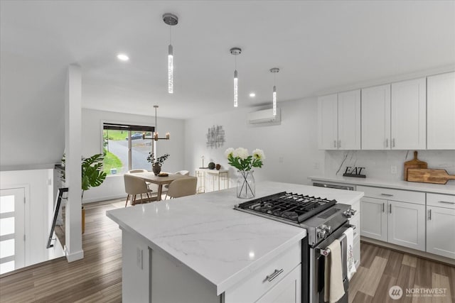 kitchen featuring stainless steel range with gas cooktop, white cabinetry, wood finished floors, and a center island