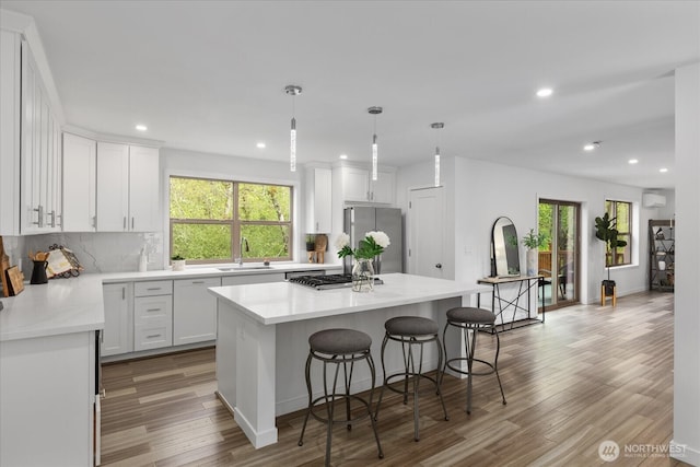 kitchen with a kitchen breakfast bar, recessed lighting, a sink, light wood finished floors, and appliances with stainless steel finishes