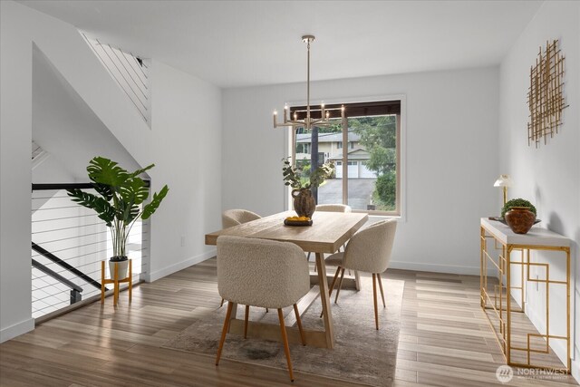 dining space with baseboards, a chandelier, and wood finished floors
