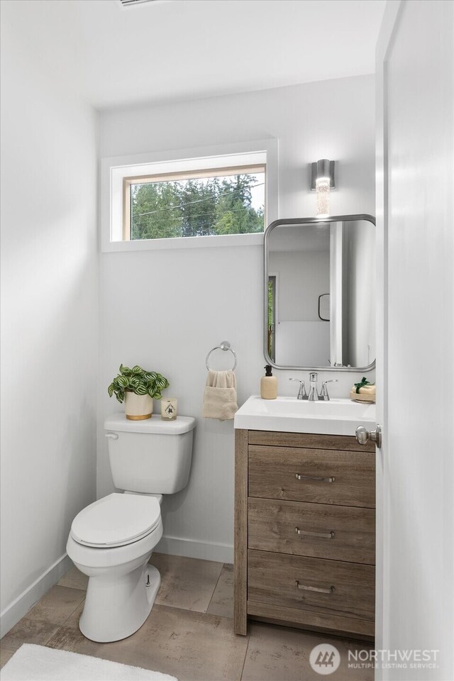 half bath with vanity, baseboards, and toilet