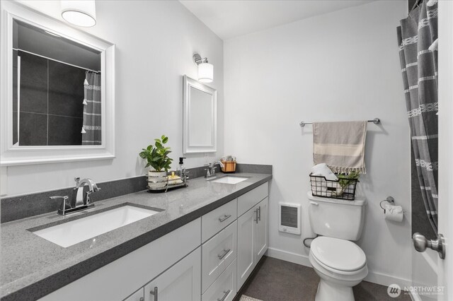 full bath featuring double vanity, a sink, heating unit, and toilet