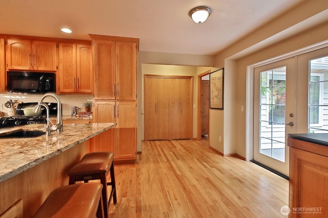 1180 Cedar Cir, Langley, WA 98260 - kitchen with black microwave, light wood-style floors, backsplash, gas range, and a sink