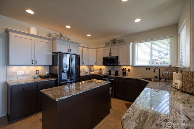kitchen featuring a kitchen island, stone countertops, appliances with stainless steel finishes, and tasteful backsplash