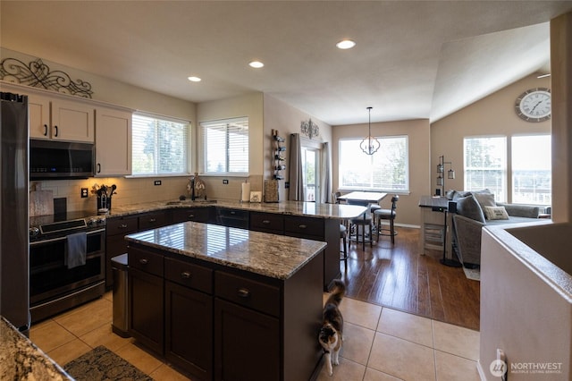 kitchen with white cabinets, light stone countertops, a sink, stainless steel appliances, and recessed lighting