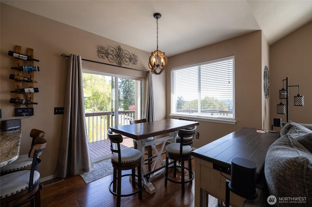 dining space with plenty of natural light, dark wood-style flooring, and a notable chandelier