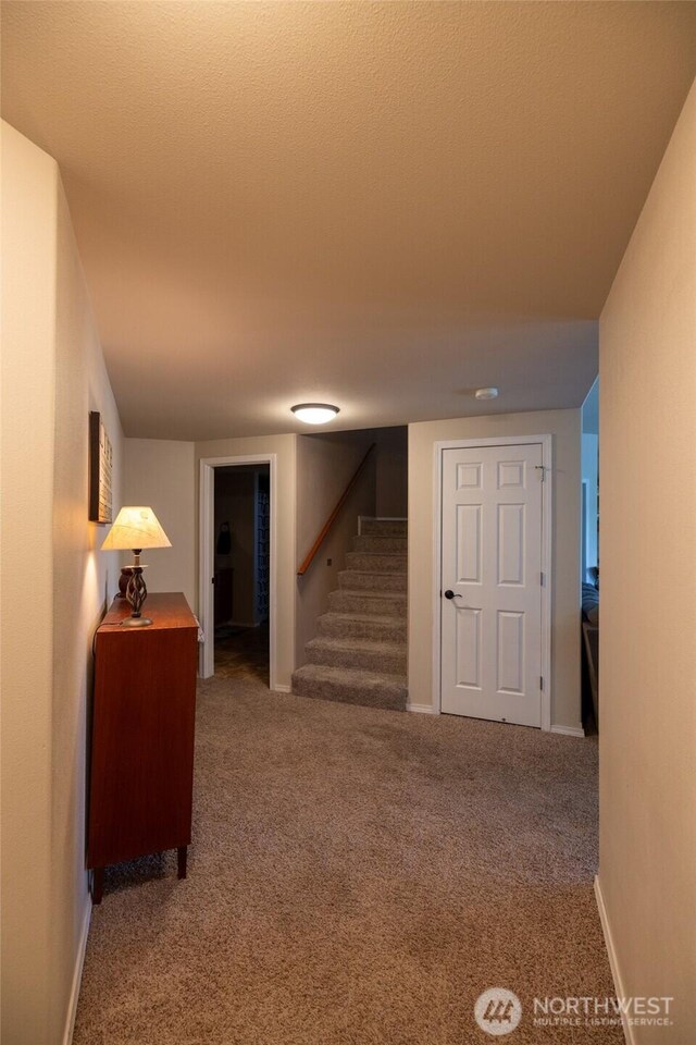 corridor with baseboards, carpet flooring, and stairs