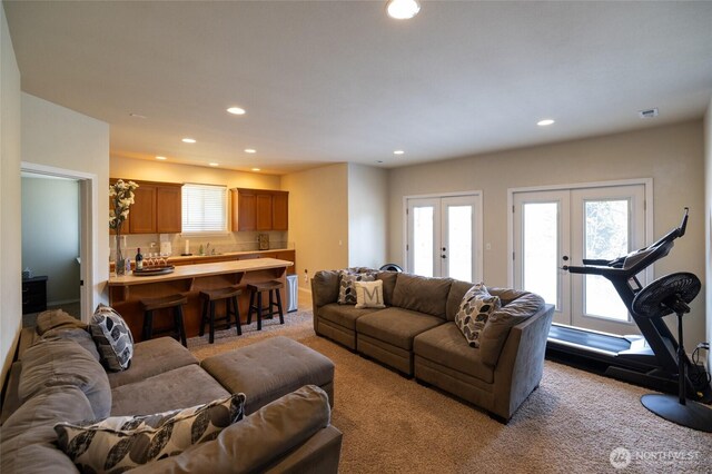 living area with recessed lighting, french doors, light colored carpet, and a healthy amount of sunlight