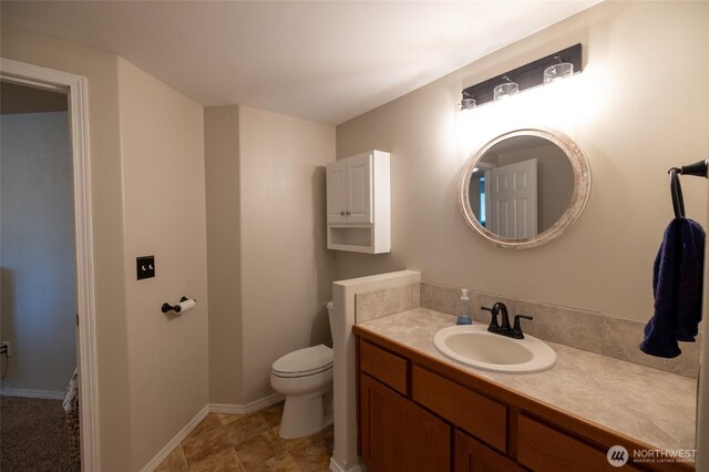 bathroom with toilet, baseboards, and vanity