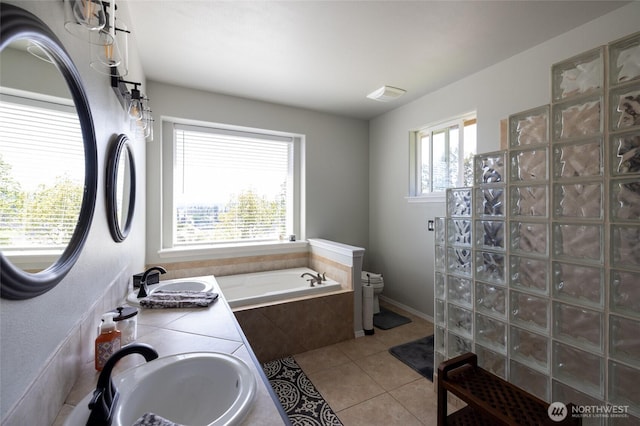 bathroom with toilet, tile patterned flooring, a sink, and a garden tub