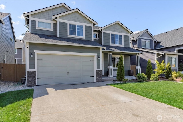 craftsman-style home featuring driveway, a front yard, a garage, fence, and stone siding