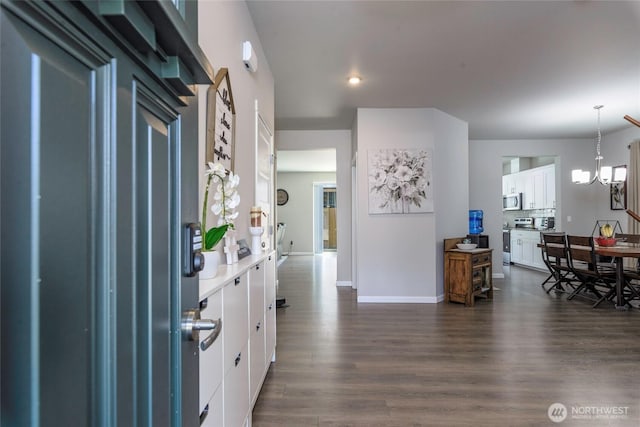 interior space featuring pendant lighting, baseboards, dark wood-style floors, white cabinets, and appliances with stainless steel finishes