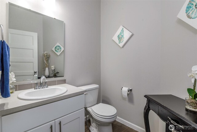 bathroom with toilet, baseboards, wood finished floors, and vanity