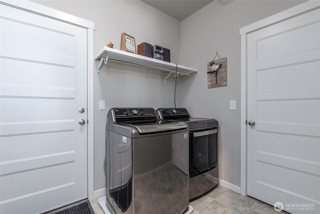 clothes washing area with baseboards, laundry area, and washing machine and dryer