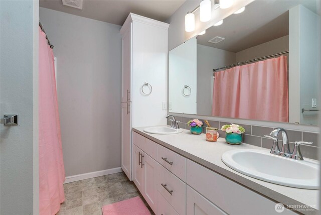 bathroom with visible vents, a sink, baseboards, and double vanity