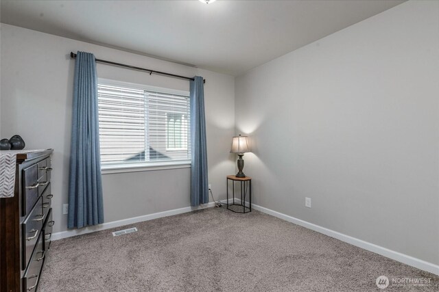 unfurnished room with baseboards, carpet, and visible vents