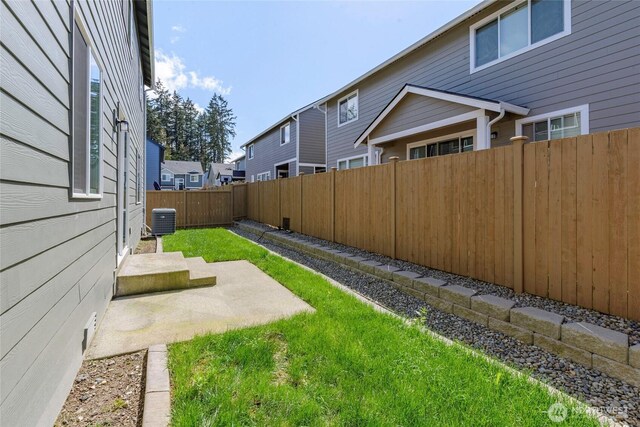 view of yard with a fenced backyard, central AC unit, and a patio