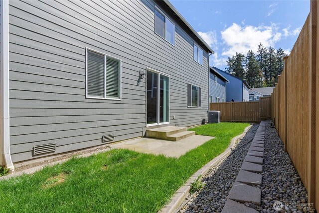 rear view of house featuring crawl space, a lawn, central air condition unit, a fenced backyard, and a patio