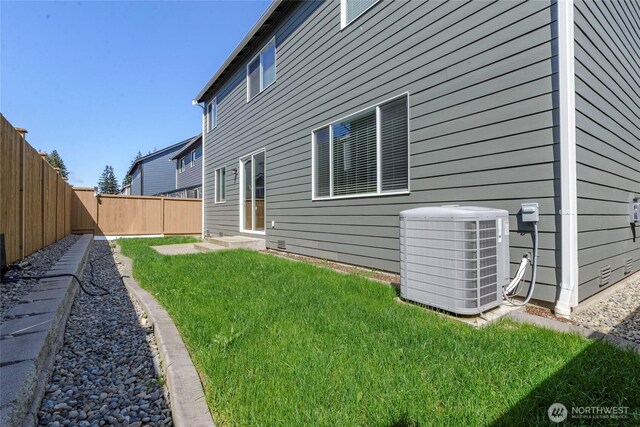 back of property with central air condition unit, a yard, and a fenced backyard