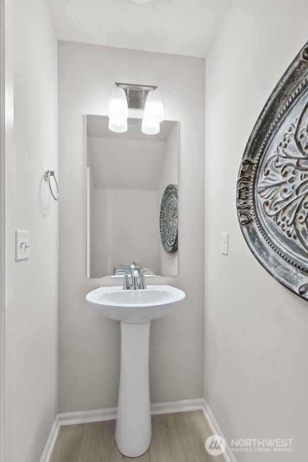 bathroom with baseboards, wood finished floors, and an inviting chandelier