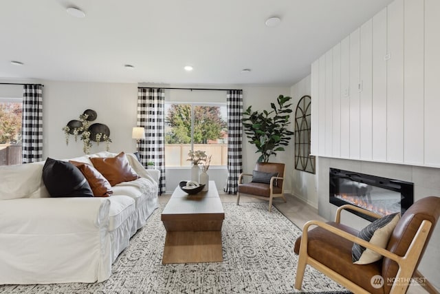 living area with baseboards and a glass covered fireplace