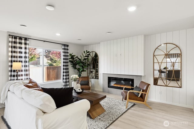 living room featuring recessed lighting, baseboards, a glass covered fireplace, and wood finished floors