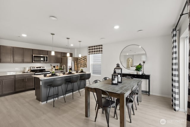 dining room featuring baseboards, recessed lighting, and light wood-style flooring