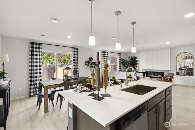 kitchen featuring a sink, light wood finished floors, dishwasher, and a healthy amount of sunlight