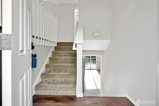 staircase featuring wood finished floors and baseboards