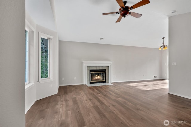unfurnished living room with vaulted ceiling, a fireplace, a ceiling fan, wood finished floors, and baseboards