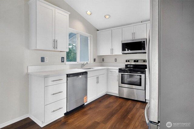 kitchen with appliances with stainless steel finishes, a sink, dark wood-style flooring, white cabinets, and light countertops
