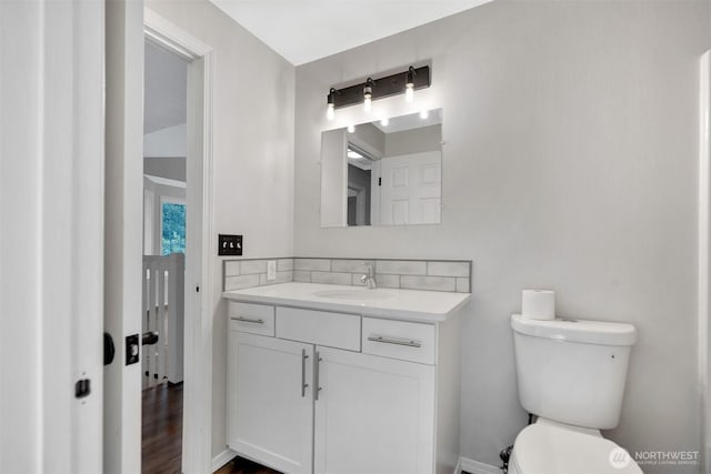 bathroom featuring toilet, vanity, baseboards, and wood finished floors