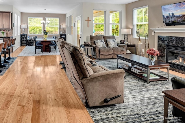 living room with an inviting chandelier, light wood-style flooring, and a fireplace
