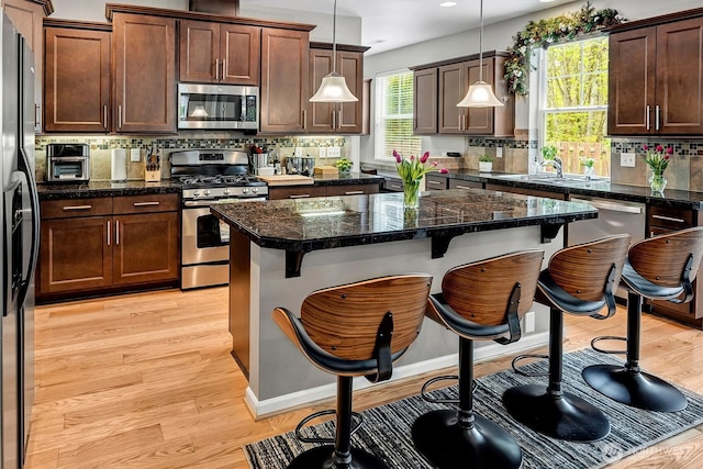 kitchen with a sink, a breakfast bar area, backsplash, and stainless steel appliances