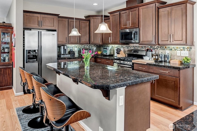kitchen with a center island, tasteful backsplash, baseboards, stainless steel appliances, and light wood-style flooring