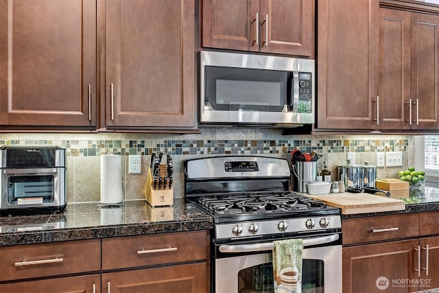 kitchen featuring dark countertops, appliances with stainless steel finishes, and backsplash