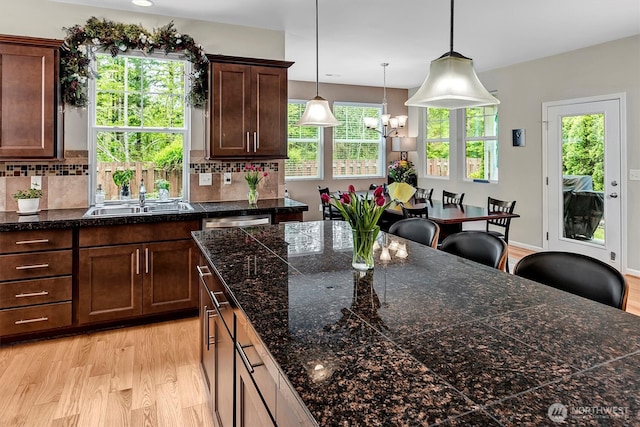kitchen featuring tile counters, a sink, light wood-style flooring, and backsplash