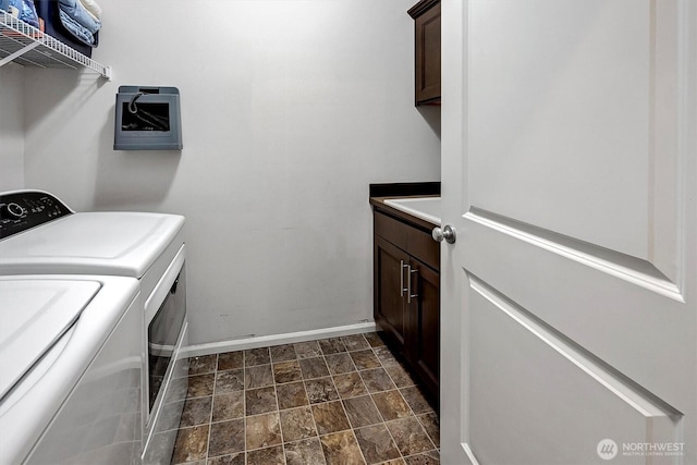 washroom with baseboards, stone finish floor, cabinet space, and washer and dryer