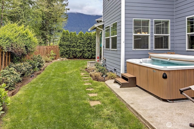 view of yard with fence, a mountain view, and a hot tub